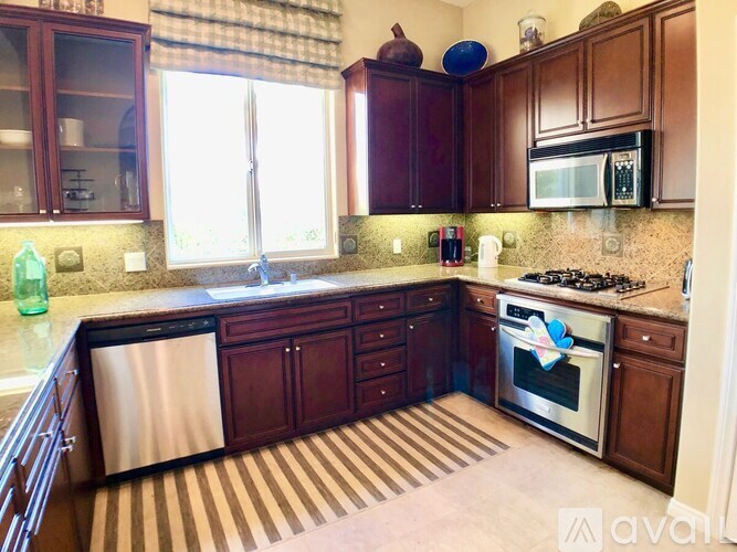 A kitchen with wooden cabinets and a stainless steel dishwasher.