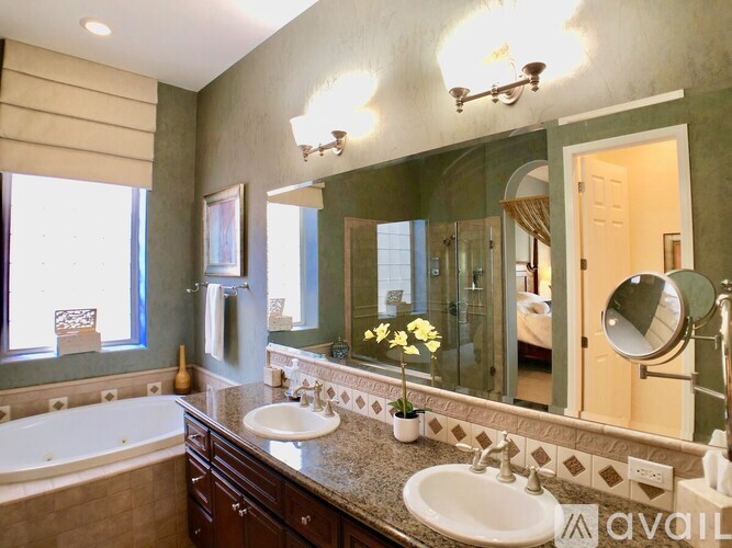 A bathroom with a tub, sink, mirror, and a window.