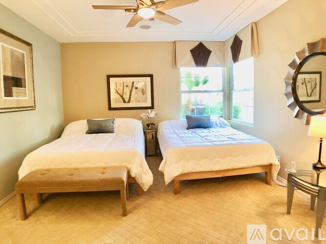 Two twin beds in a room with a ceiling fan.