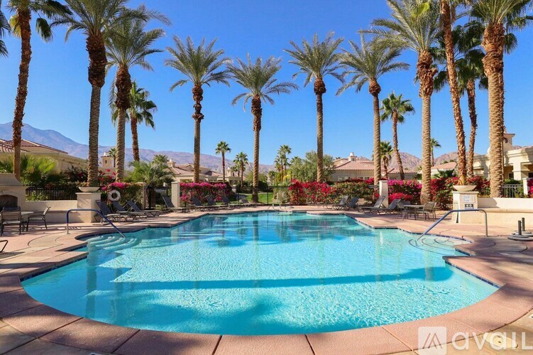 A pool surrounded by palm trees and red flowers.