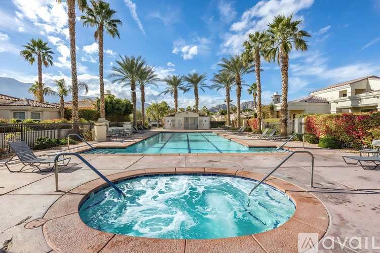 A pool surrounded by palm trees and a mountain in the distance.