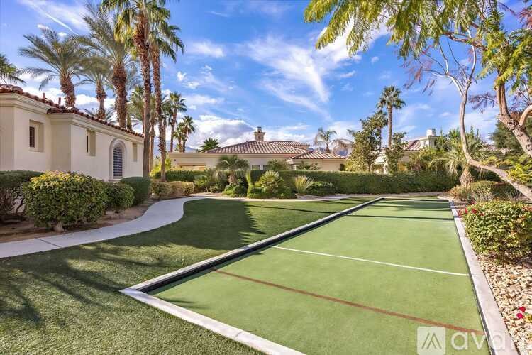 A tennis court surrounded by palm trees and a white house.