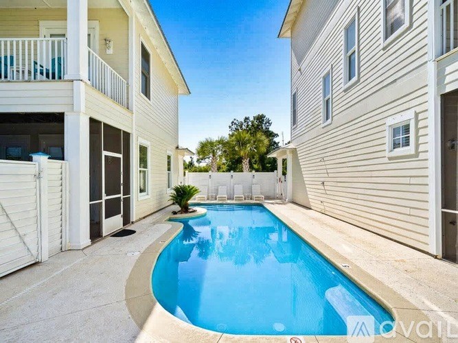 A pool in a backyard surrounded by two houses.