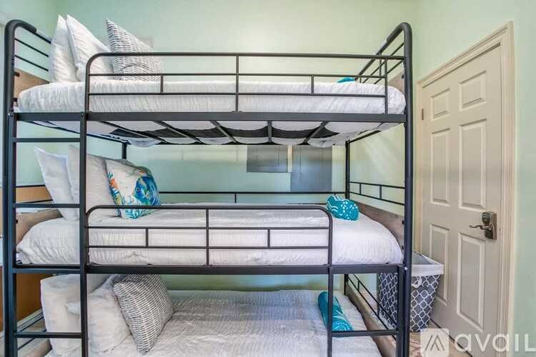 A bunk bed with a white mattress and pillows is in a room with a door.