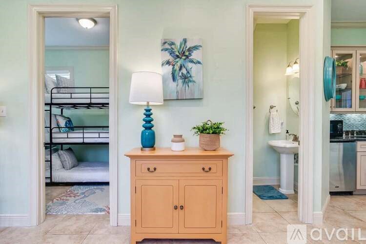 A room with a bunk bed, a dresser, and a painting on the wall.