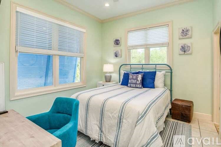 A bedroom with a bed, chair, and window.