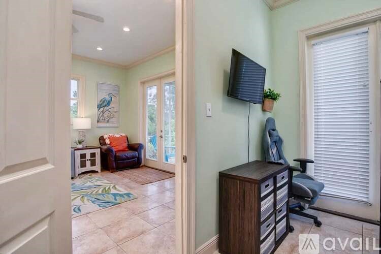 A room with a TV on the wall and a chair in front of it.