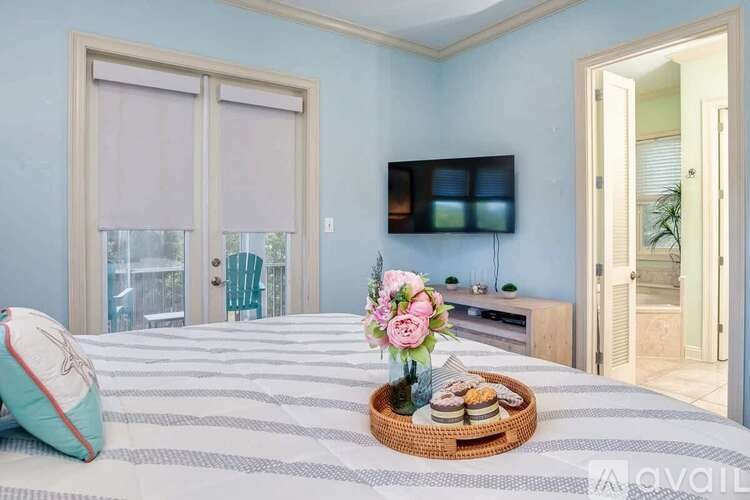 A bedroom with a bed, a chair, a TV, and a basket of food on the bed.