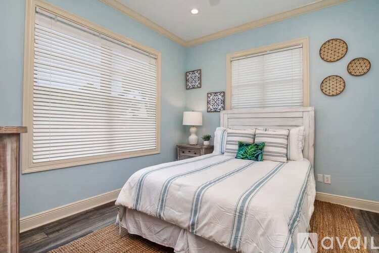 A bedroom with a bed, nightstand, and window with blinds.