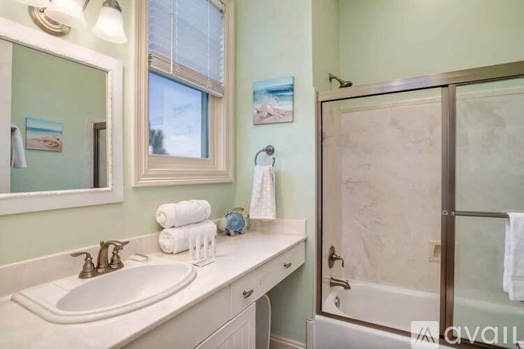 A bathroom with a sink, mirror, and shower.