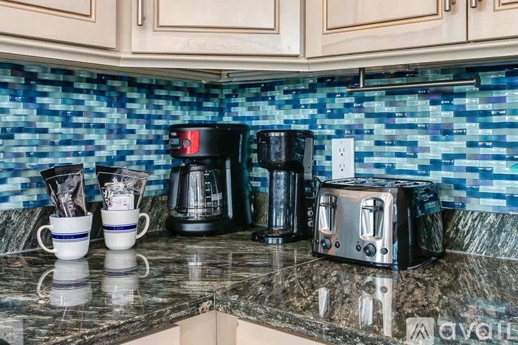 A kitchen counter with a toaster, coffee maker, and cups.