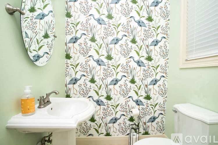A bathroom with a green wall and a shower curtain with birds and plants on it.