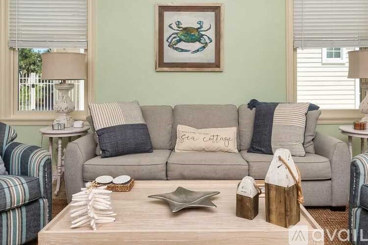 A living room with a grey couch, a wooden coffee table, and a painting of a crab on the wall.