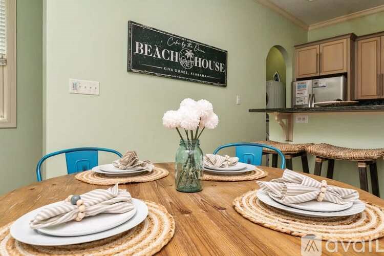 A dining table set with plates and napkins in front of a sign that says "Beach House".