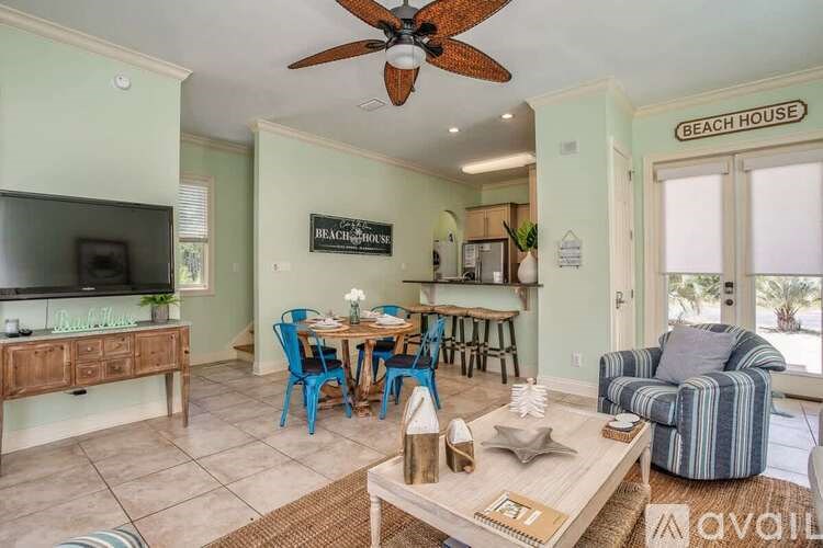 A living room with a dining table and chairs, a television, and a ceiling fan.