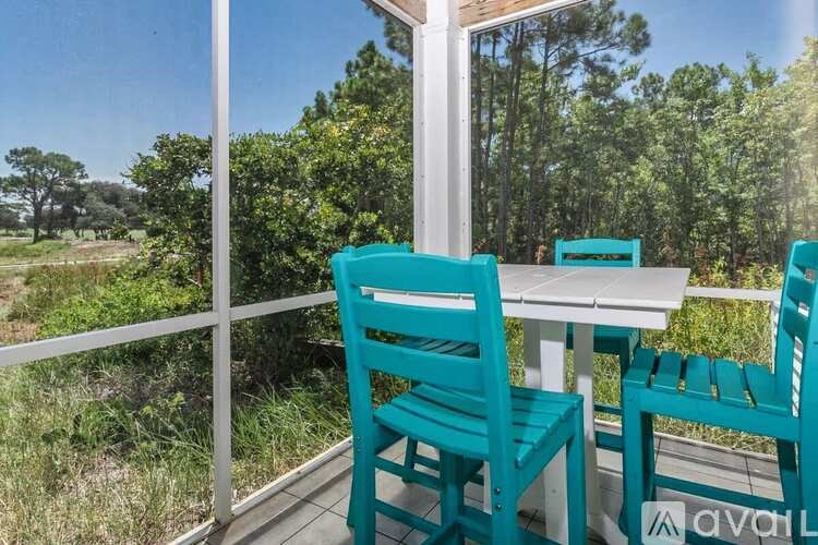 A table and two chairs are set up on a balcony with a view of trees.