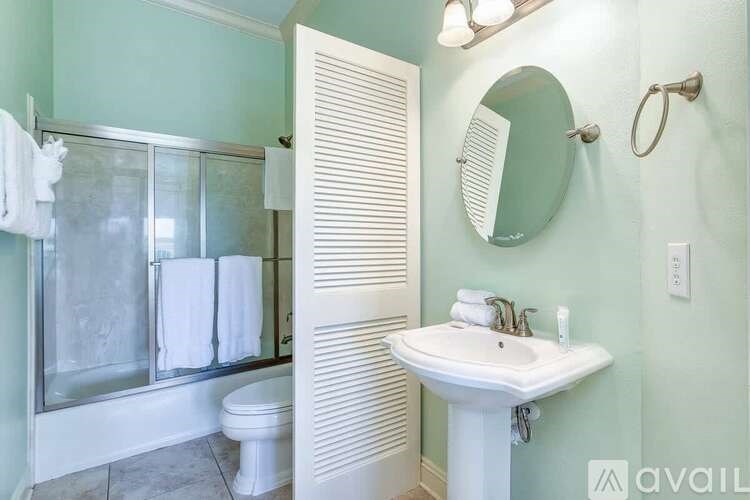A bathroom with a white sink, toilet, and a glass shower stall.