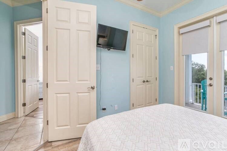 A bedroom with a bed, a television, and a sliding glass door.