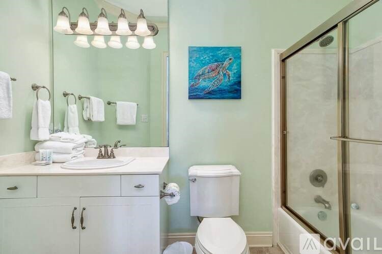 A bathroom with a white toilet, sink, and a painting of a whale on the wall.