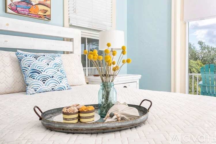 A tray with pastries and a vase with yellow flowers on a bed.