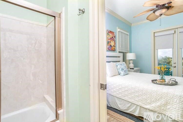 A bedroom with a bed, a ceiling fan, and a window.