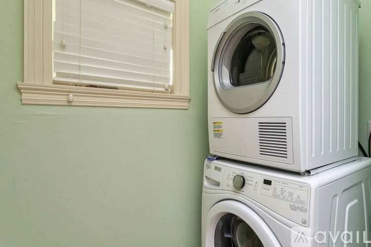 A stack of two white washing machines in a room with a window.