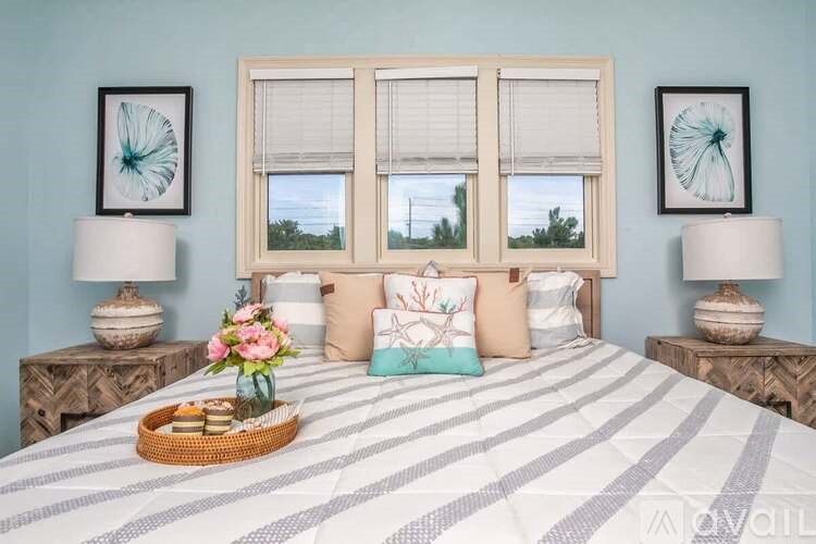 A bedroom with a large bed, striped bedspread, and two lamps on side tables.