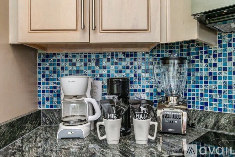A kitchen counter with a coffee maker, a blender, and two mugs.