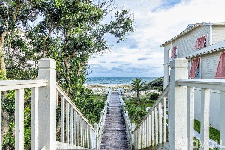 A white house with a balcony overlooking a beach.
