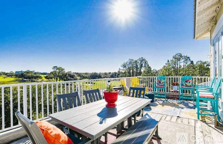 A sunny day at a wooden deck with a table and chairs.