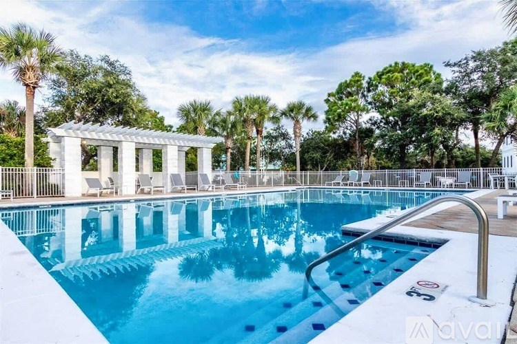 A pool with a white pergola and palm trees in the background.