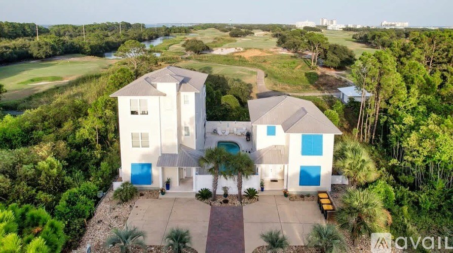 A large white house with a pool in the middle of a green landscape.