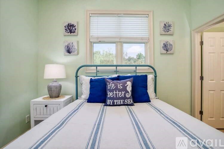 A bedroom with a bed, nightstand, and a window with a view of the sea.