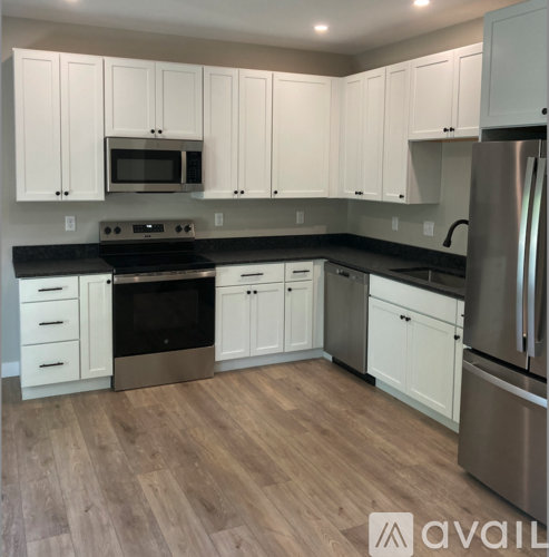 A kitchen with white cabinets and a wooden floor.