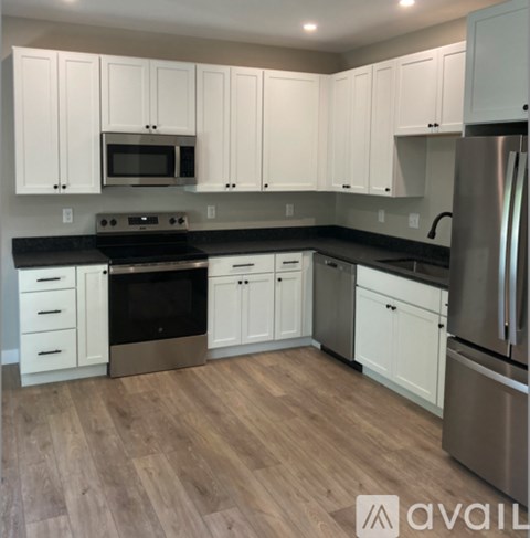 A kitchen with white cabinets and a wooden floor.