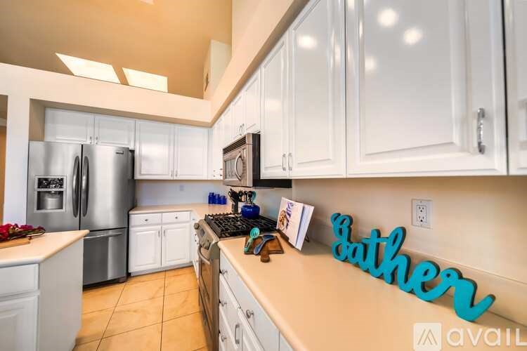 A kitchen with white cabinets and a refrigerator.