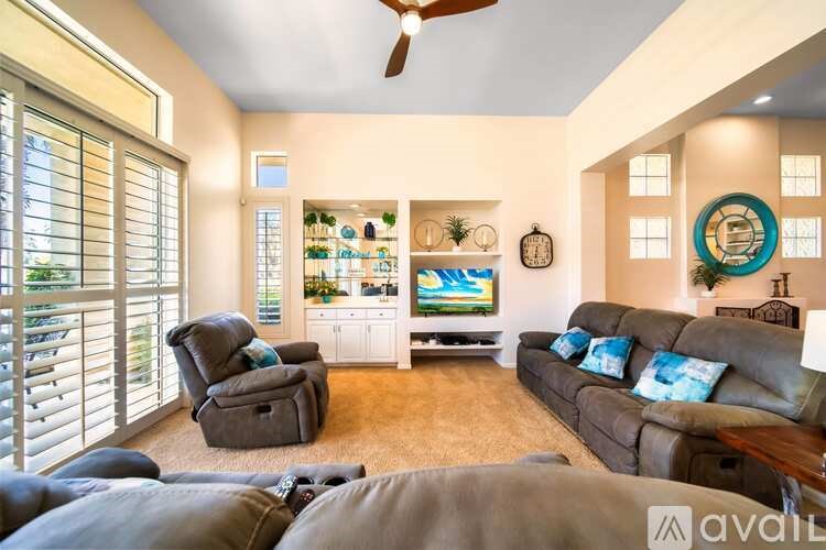 A living room with a grey couch and a fan.