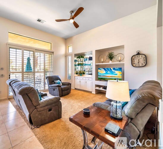A living room with a brown leather couch, a wooden coffee table, and a ceiling fan.