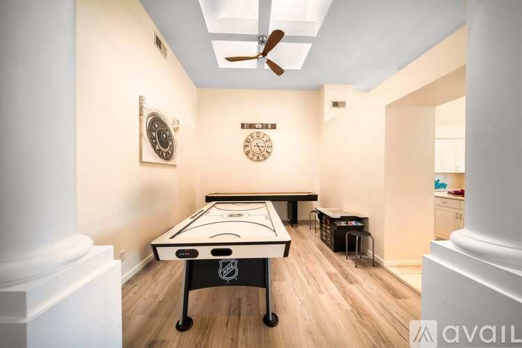 A pool table is in the middle of a room with a clock on the wall.