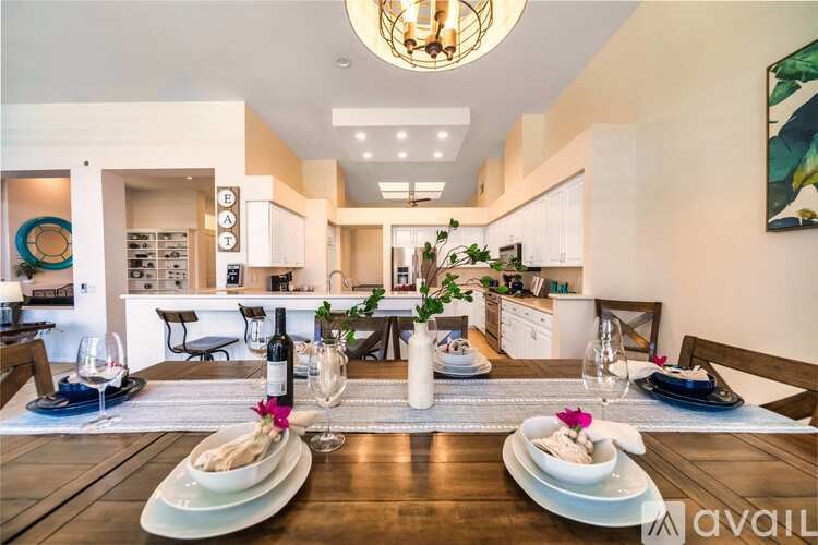 A dining room with a table set for two with a bottle of wine and a vase of flowers.