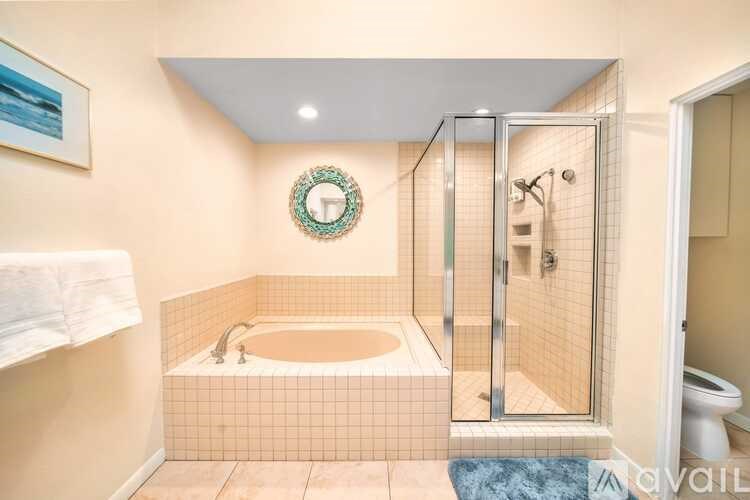 A bathroom with a glass shower door and a round mirror on the wall.