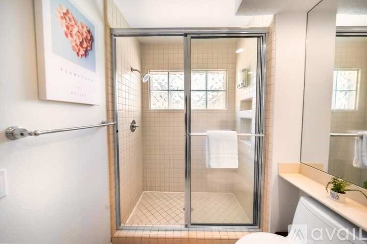 A bathroom with a glass shower door and a tiled floor.