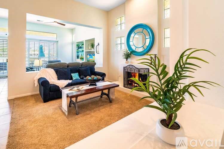 A living room with a black couch, a coffee table, and a plant.