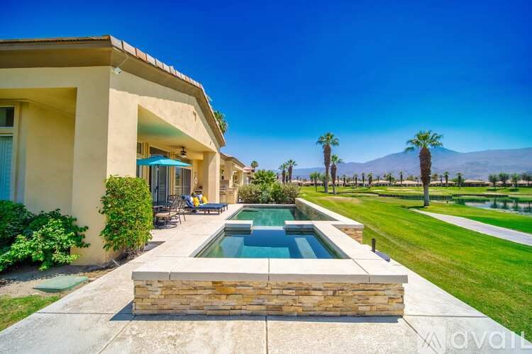 A house with a pool in the foreground and palm trees in the background.