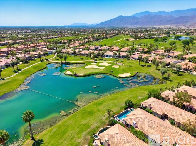 A golf course with a lake and houses in the background.