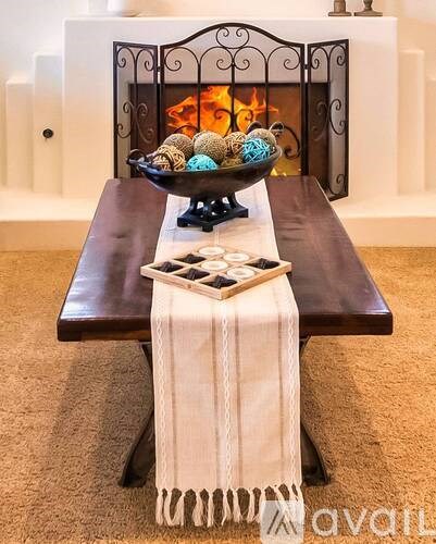 A bowl of decorative items sits on a table in front of a fireplace.