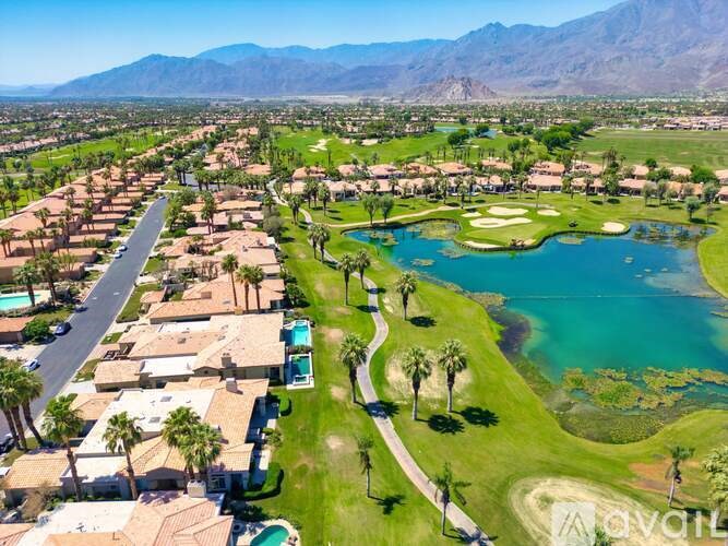A golf course surrounded by houses with a mountain in the background.