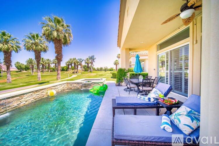 A pool with a table and chairs is in front of a house.