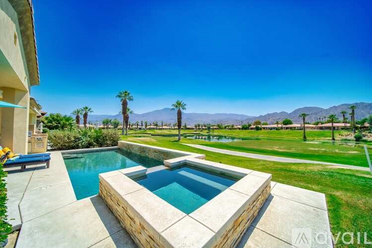 A pool surrounded by a concrete wall with a mountain in the background.