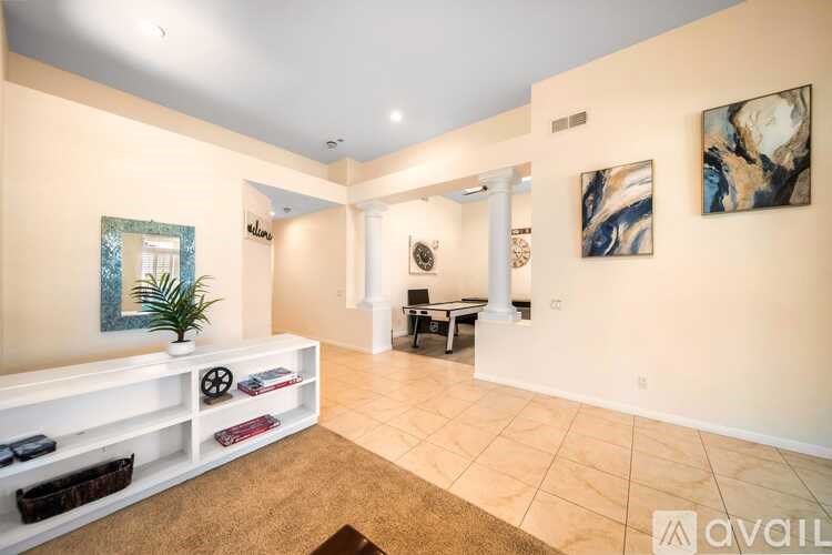 A living room with a white couch and a painting on the wall.